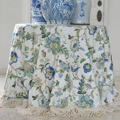 two vases on top of a table covered with a blue and white floral fabric