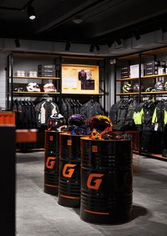 the inside of a clothing store with several black barrels