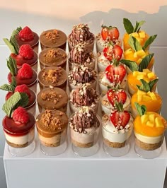 an assortment of desserts are arranged on a white display stand with fruit and chocolate toppings