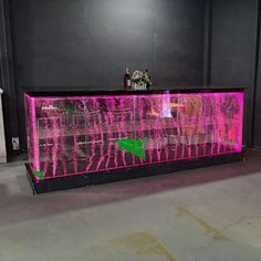 a pink and black bar with neon lights on it's sides, in a dark room