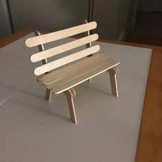 a small wooden bench sitting on top of a white sheet covered floor next to a wall