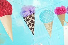 ice cream cones and paper flowers are hanging from a line