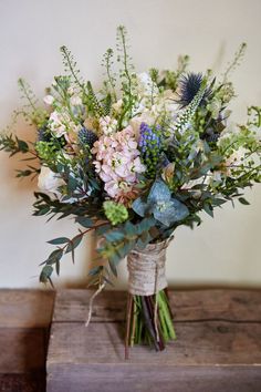 a vase filled with lots of flowers on top of a wooden table