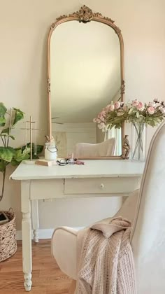 a white desk with a mirror, chair and potted plant in front of it