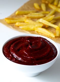 a white bowl filled with ketchup next to french fries