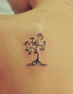 a small tree tattoo on the back of a woman