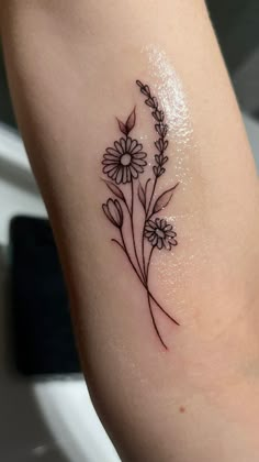 a small flower tattoo on the arm