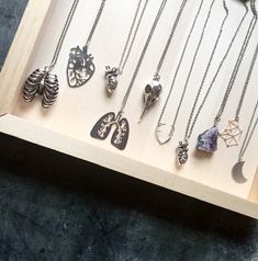 there are many different necklaces on display in the box with it's shadow