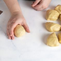 a person is kneading dough into small pieces on a white counter with several other hands