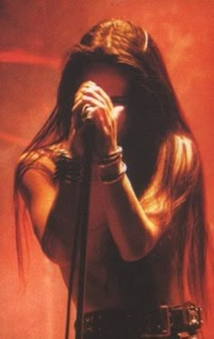 a woman with long hair holding a microphone in front of her face while standing on stage