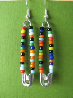 two pairs of colorful beaded earrings hanging from hooks on a green cloth covered surface