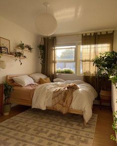 a bed room with a neatly made bed and potted plants on the windowsill