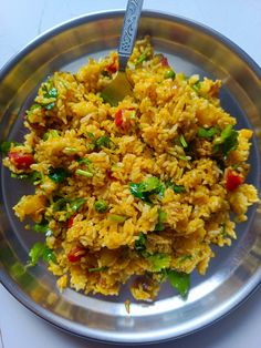 a silver plate topped with rice and veggies on top of a white table