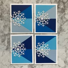 four snowflakes cut out of blue and gray paper on a marble surface