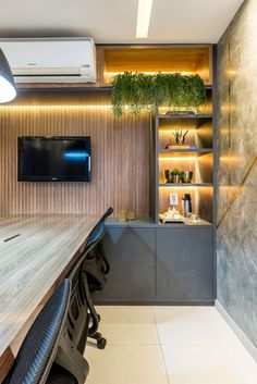 an empty conference room with a flat screen tv on the wall and wooden desks