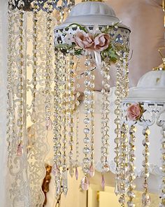 two chandeliers hanging from the ceiling with flowers and pearls attached to each one