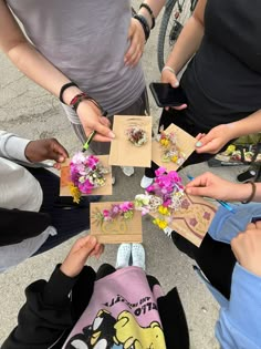 a group of people standing around each other with flowers in their hands and cards on the ground