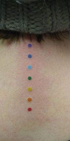 the back of a woman's neck with multicolored dots on it