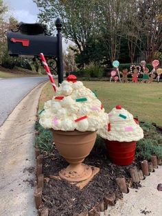 two ice cream sundaes sitting on top of a flower pot in front of a mailbox