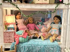 three dolls sitting on top of a bed next to each other in a doll house