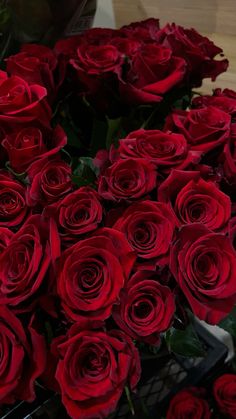 a bunch of red roses sitting on top of a wooden table next to each other