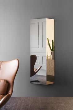 a chair is sitting in front of a mirror with a plant on it and a potted cacti