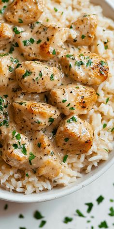 a white bowl filled with rice and chicken covered in gravy, garnished with parsley