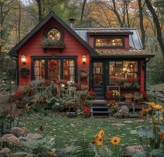 a red house in the woods with lots of flowers