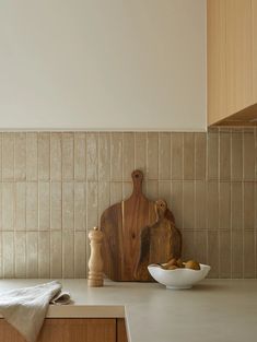 a wooden cutting board sitting on top of a counter next to a bowl of fruit