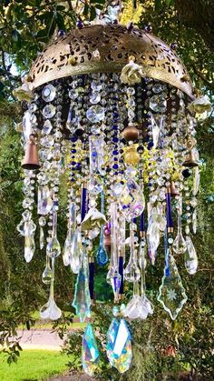 a chandelier hanging from a tree with lots of glass beads and other items