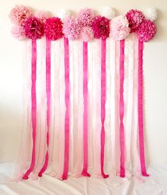 pink and white flowers hanging from the side of a wall with ribbons on it's sides