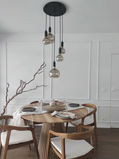 a dining room table with chairs, plates and candles hanging from it's ceiling