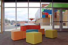 an office lobby with colorful furniture in front of large windows that overlook the parking lot