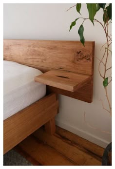 a bed with a wooden headboard next to a plant