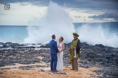 two men and a woman are standing on the beach with waves crashing in the background