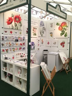 a booth with flowers and cards on the walls, in front of a green carpeted floor