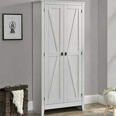 a white armoire in a room with gray walls and wood flooring, along with a wicker basket on the floor