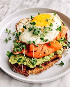 an open face sandwich with eggs, tomatoes and avocado on toasted bread