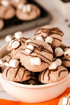 a bowl filled with cookies and marshmallows on top of an orange napkin