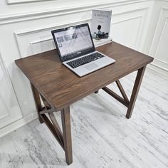 an open laptop computer sitting on top of a wooden desk next to a book and magazine