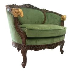 an ornate green chair with gold detailing on the armrests and foot rests against a white background