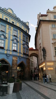 people are walking around in front of some colorful buildings on a cobblestone street