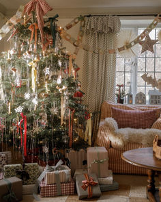 a decorated christmas tree in a living room with presents under it and other holiday decorations