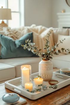 a tray with candles on top of it in front of a couch and coffee table