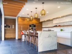 an open kitchen and dining area with marble counter tops, bar stools, and wood paneling