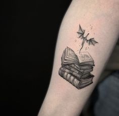 a black and white photo of a book tattoo on the arm