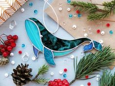 a glass ornament sitting on top of a table next to pine cones and berries