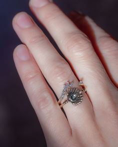 a woman's hand with a ring on it that has a seashell in the middle