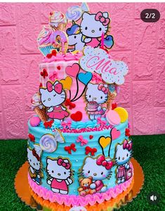 a hello kitty birthday cake with lots of decorations on the top and bottom tiers