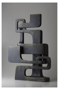 a sculpture made out of metal on a white surface with grey background and gray wall behind it